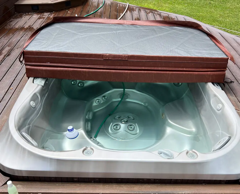 A hot tub with the lid open and water inside.