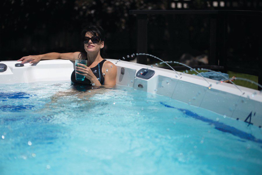 A woman in the pool drinking water from a bottle.